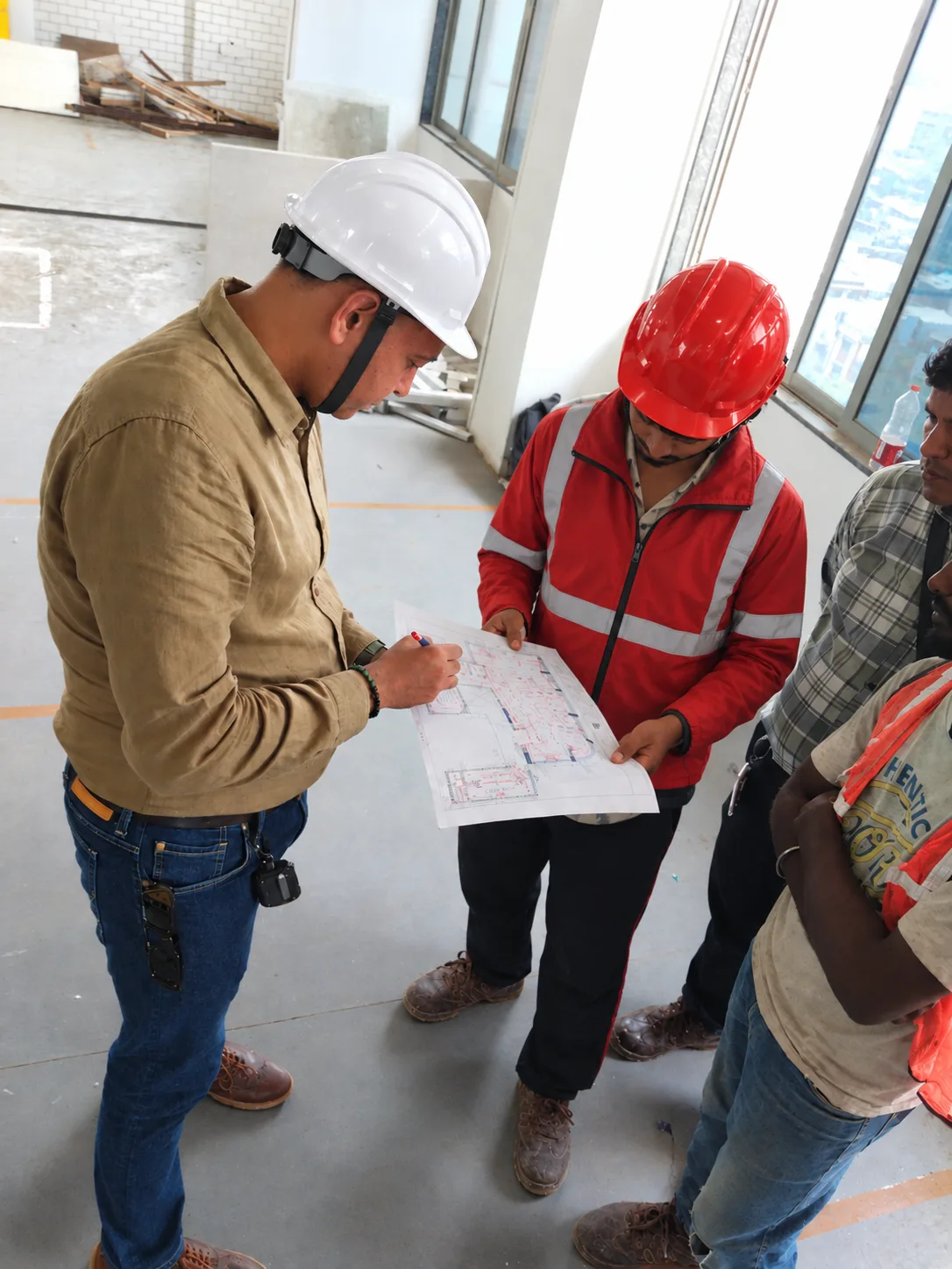 Engineer marking up a services drawing with the site team on a live floor plate