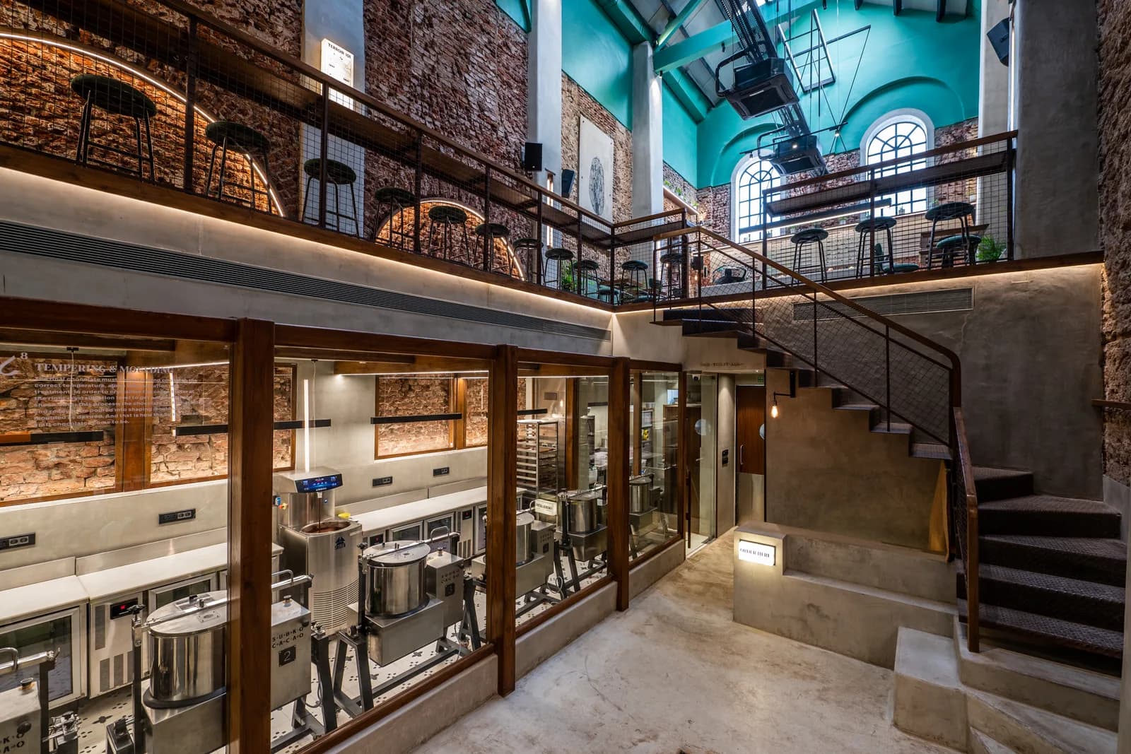 A completed double-height fit-out with exposed services, feature lighting and a mezzanine